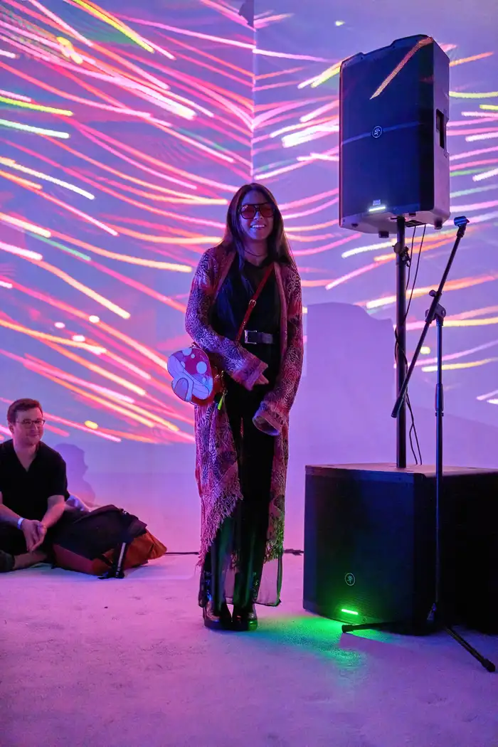 An attendee standing in the venue amid projected light trails